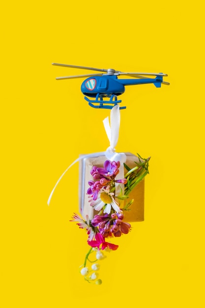 Foto papel amarillo caja regalo juguete entrega helicóptero fondo amarillo mosca flores