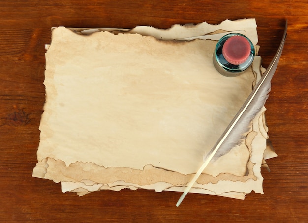 Papel antiguo, tinta y pluma sobre mesa de madera