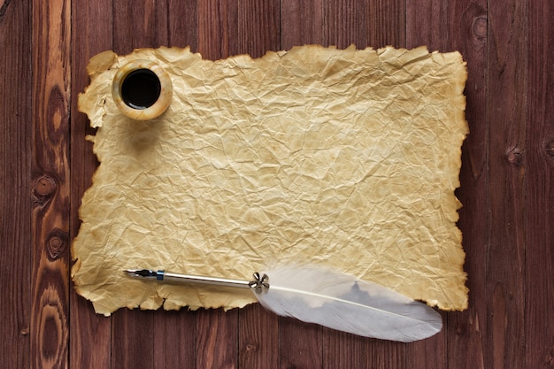 Papel antiguo y tintero con pluma sobre un fondo de madera