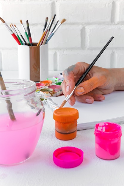 Papel, aquarelas, pincel e algumas coisas de arte na mesa de madeira