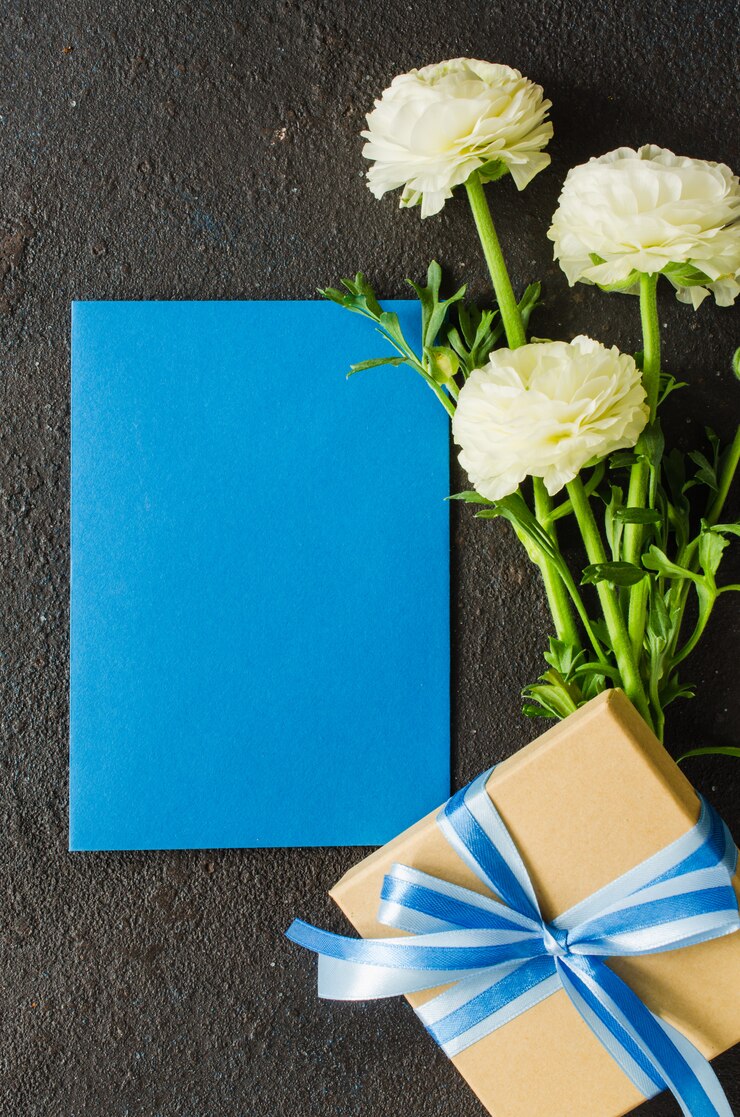 Foto papel azul en blanco, caja de regalo y ramo de flores blancas
