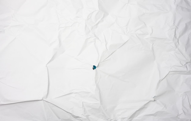 Foto papel blanco arrugado, pliegues y un agujero.