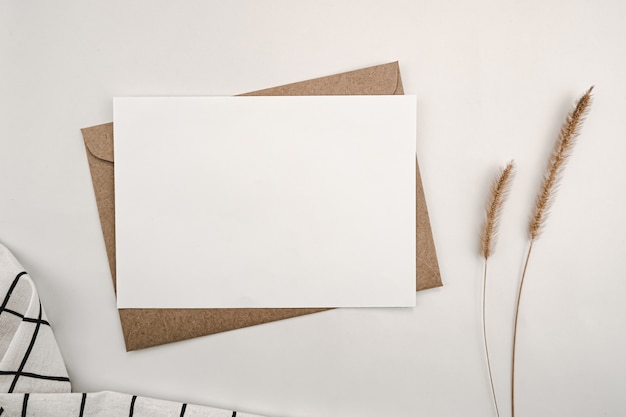 Foto papel blanco en blanco sobre papel marrón con flor seca de cola de zorro erizada y rejilla negra de tela blanca