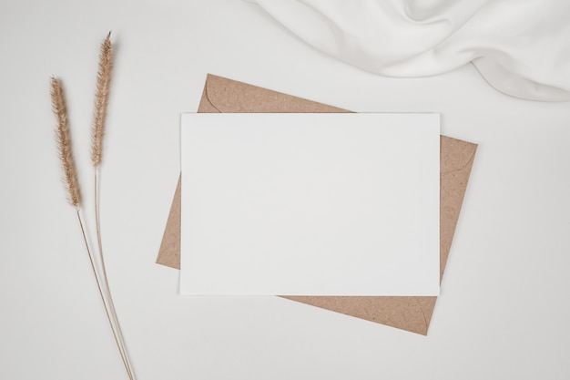 Papel blanco en blanco sobre papel marrón con flor seca de cola de zorro erizada sobre tela blanca