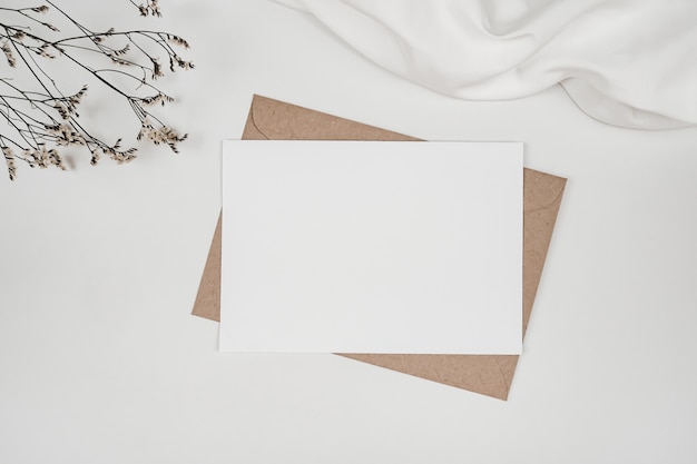 Foto papel blanco en blanco sobre papel marrón con flor seca de limonium sobre tela blanca