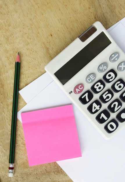 Papel blanco con calculadora lápiz y memo en la mesa de madera