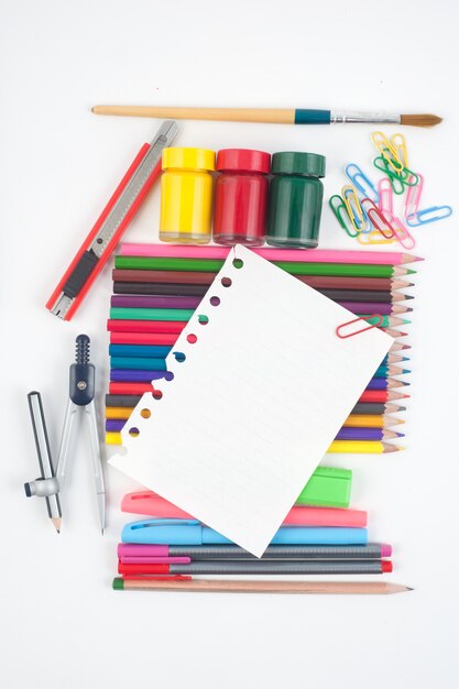 Papel en blanco y las herramientas de la escuela o la oficina en el fondo blanco