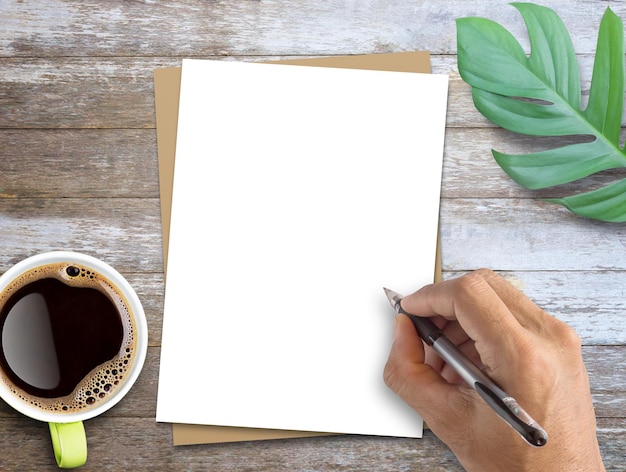 Papel blanco y marrón en blanco y hojas verdes frescas sobre fondo de mesa de madera