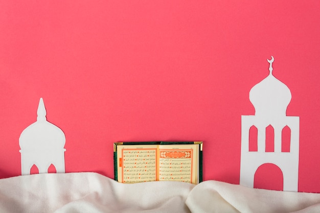 Foto papel blanco de la mezquita cortado con un sagrado kuran islámico sobre el fondo rojo