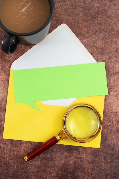 Papel en blanco con taza de café de sobre con forma de burbuja de voz y lupa colocada en la mesa que representa importantes estrategias de marketing para objetivos comerciales