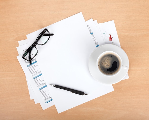 Papel en blanco con vasos de pluma y taza de café.