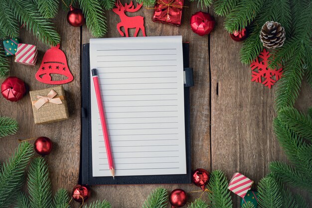 Foto papel de bloc de notas de pantalla en blanco con fondo de navidad con adornos en tablero de madera.