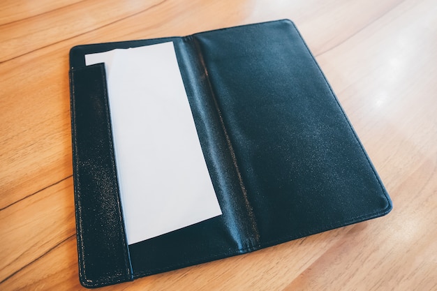 papel branco em couro preto pasta de recibo de cobrança de pagamento na mesa de madeira