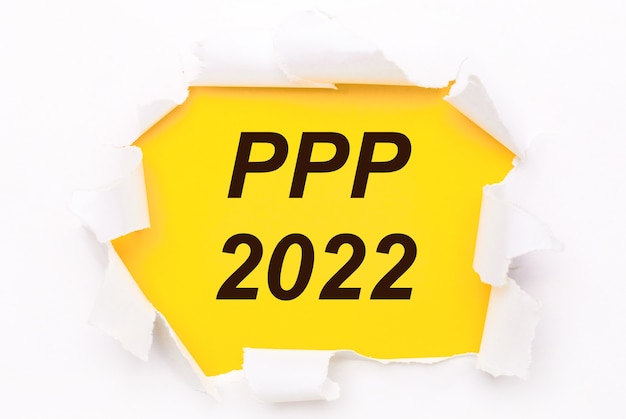 Papel branco rasgado repousa sobre um fundo amarelo brilhante com o texto PPP 2022