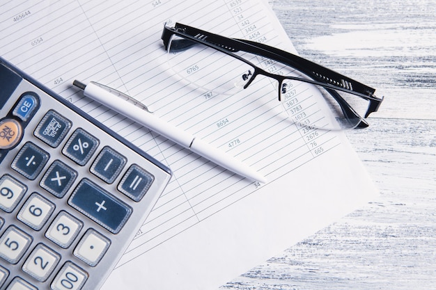 Papel, calculadora e óculos em cima da mesa. conceito de desktop