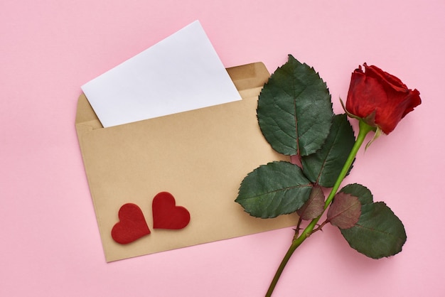 Papel de carta de amor con sobre rosa roja y corazones decorativos