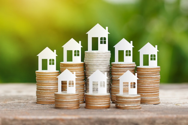 Papel de la casa en la pila de monedas para el ahorro para comprar una casa
