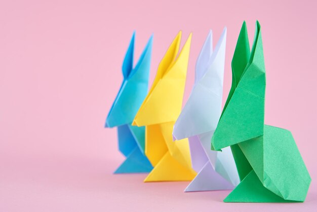 Foto papel colorido origami esater coelhos em fundo rosa conceito de celebração de páscoa