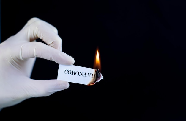 Papel com o texto Coronavirus está queimando na mão O conceito de derrotar o Coronavirus