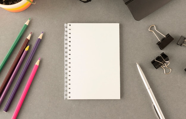 Papel de cuaderno sobre mesa gris y lápices de colores