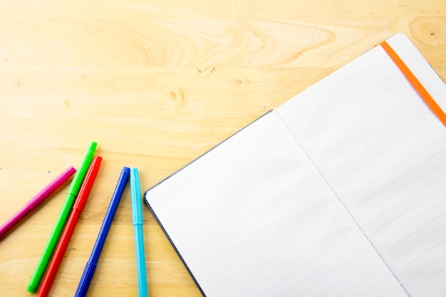 papel de caderno e caneta de cor na mesa de madeira. De volta à escola.