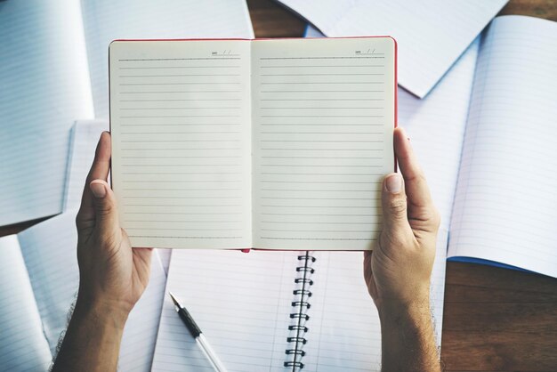 Papel de mãos e caderno em vista superior na mesa para planejar escrita e brainstorming de ideias no escritório Notas de pessoa e livros de cima na mesa para inspiração de inicialização de diário e lançamento de negócios