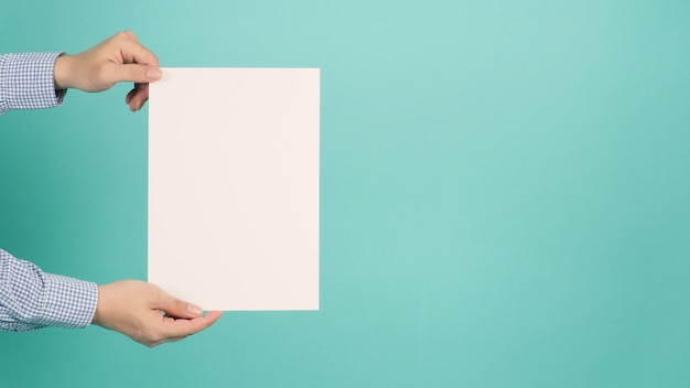 Papel de tabuleiro em branco ou vazio A4 nas mãos do homem na hortelã verde ou azul Tiffany background.man usar camisa azul.