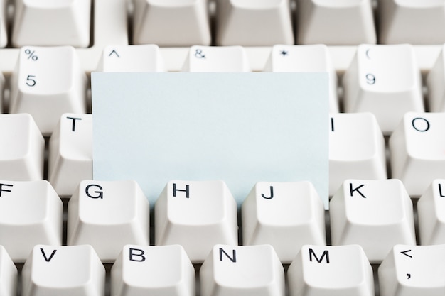 Foto papel desobstruído empilhado no teclado de computador branco.