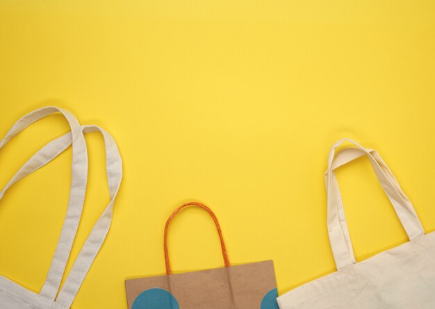 Papel e bolsa de tecido bege vazia em fundo amarelo