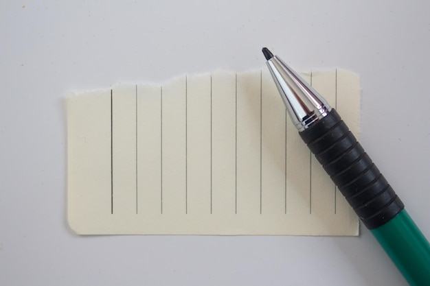 Papel em branco com caneta sobre fundo branco. vista superior do pedaço de papel com espaço de cópia.