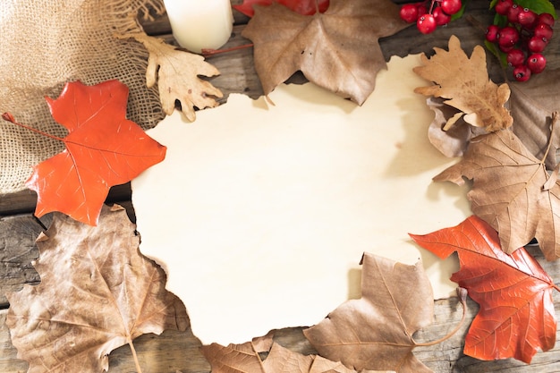 Foto papel con espacio para copiar, hojas de otoño y bayas sobre una superficie de madera contra una superficie de madera. concepto de fiesta y celebración de halloween