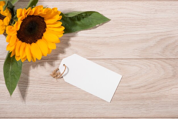 Papel de etiqueta blanco en blanco con flores de colores sobre fondo de madera. Vista superior. Bosquejo