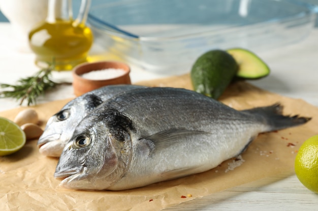 Papel para hornear con peces Dorado e ingredientes para cocinar en madera