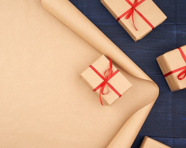 Papel kraft marrón, cajas de regalo empaquetadas y atadas con una cinta roja, corazón rojo, un conjunto de artículos para hacer regalos