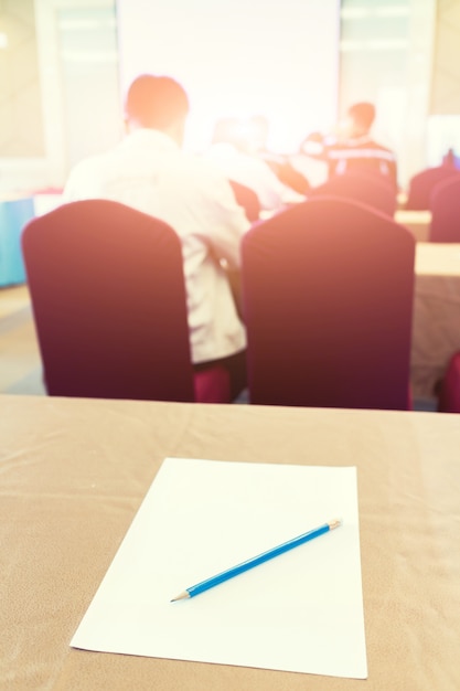 Papel, lápis sobre a mesa no fundo da sala de seminário