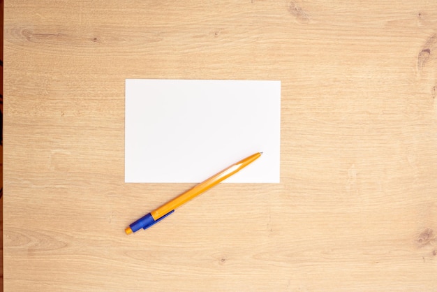Papel de nota blanco o tarjetas y un bolígrafo amarillo sobre una mesa de madera. Nota pancarta.