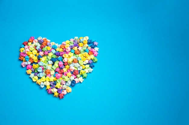 Foto papel plegado en forma de una estrella multicolor de cinco puntas sobre un fondo azul dispuesto en forma de corazón