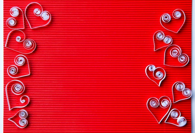 Papel quilling sobre cartulina roja. Fondo con corazones para el día de San Valentín.