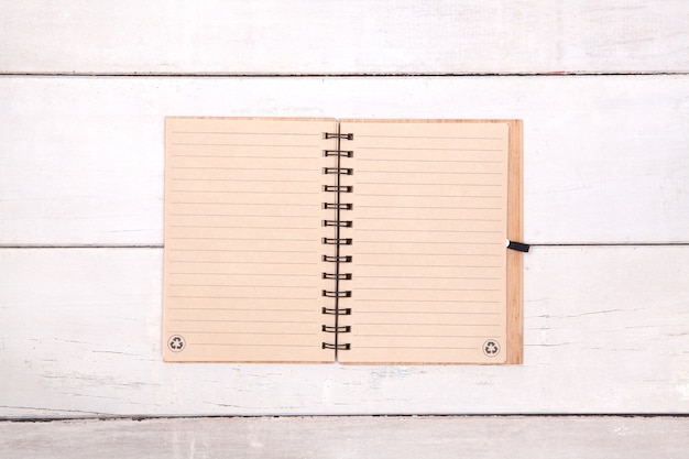 Papel reciclado de caderno em branco na mesa de madeira.