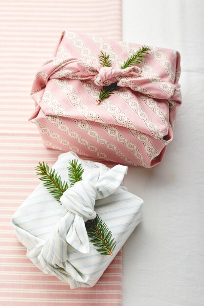 Papel de regalo ecológico de Navidad en estilo tradicional japonés furoshiki decorado con ramitas de abeto sobre fondo de tela, papel de regalo ecológico y concepto Zero Wast