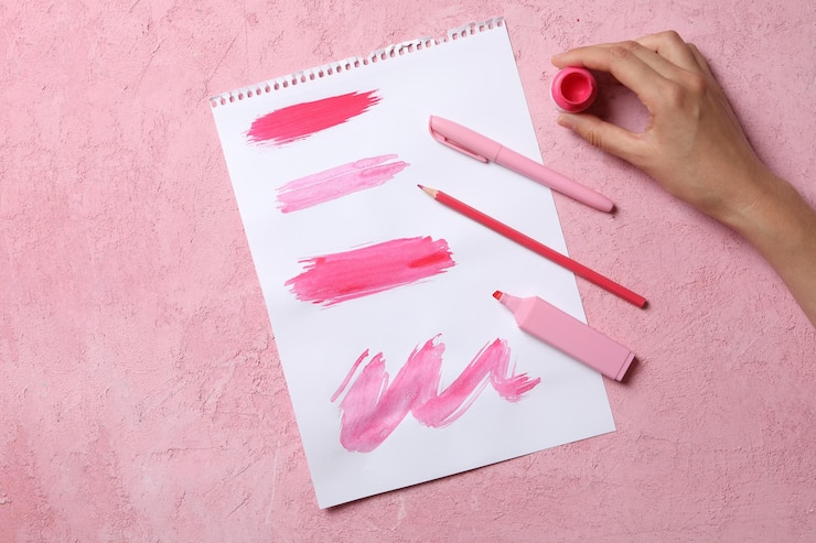 Foto papel con trazos de pintura y mano en la vista superior de fondo rosa