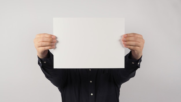 Papel vacío en blanco en la mano del hombre y usar camisa azul marino