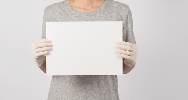 Papel vazio em branco na mão da mulher e usar luva médica em fundo branco.