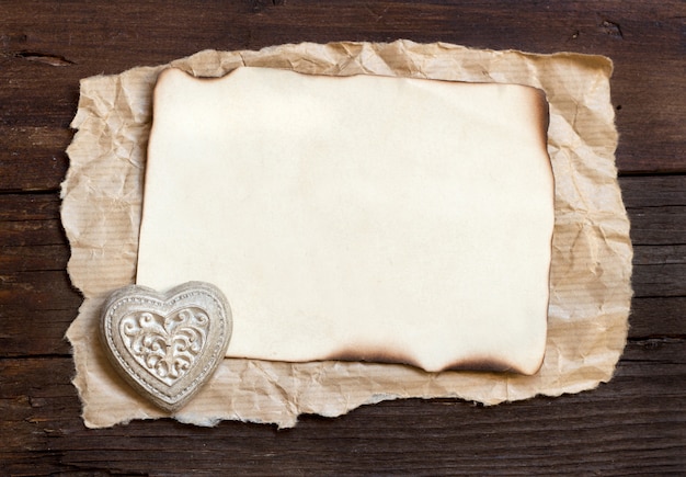 Foto papel viejo y un corazón sobre un fondo de madera marrón