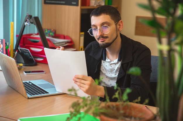 Papeleo. Empresario caucásico, empresario, gerente que trabaja concentrado en la oficina. Parece serio y ocupado, con atuendo clásico. Concepto de trabajo, finanzas, negocios, éxito, liderazgo.