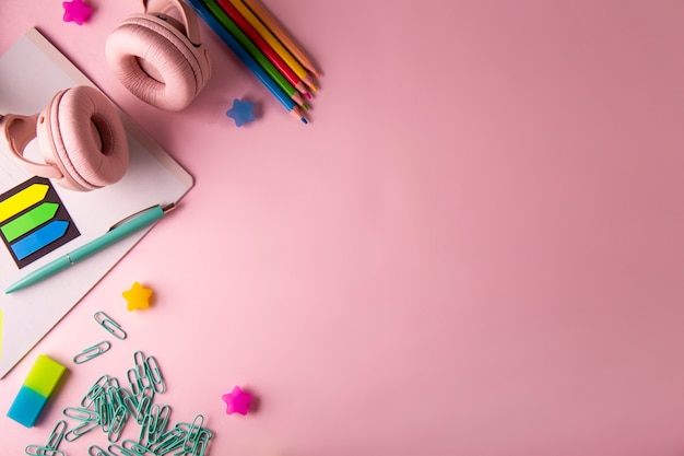 Papelería y auriculares sobre fondo rosa concepto de regreso a la escuela con espacio para copiar texto