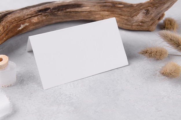 Papelería de boda maqueta de tarjeta en blanco, sobre fondo de mesa de piedra gris con decoración de madera, blog femenino plano, maqueta de estilo bohemio simple maqueta de tarjeta en blanco plegada de 3,5x2