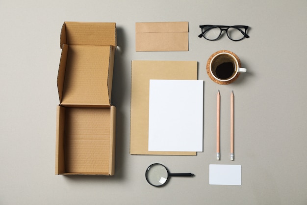 Papelería corporativa, gafas y lupa sobre fondo gris.