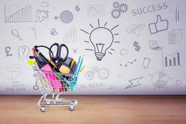 Foto papelería dentro de un carrito de compras con garabatos en el fondo de la pared concepto de regreso a la escuela