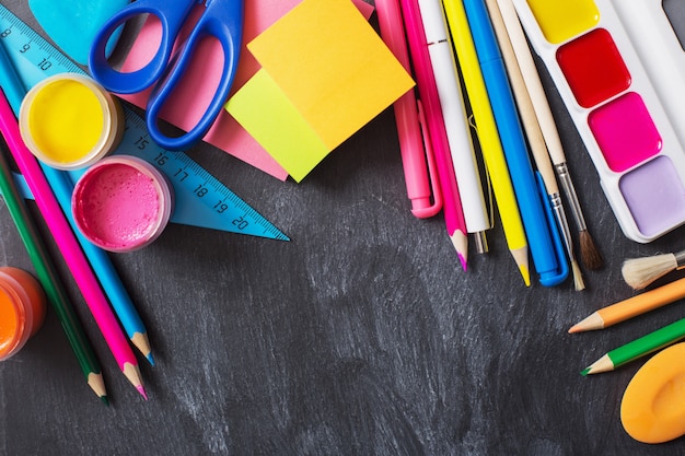 Papelería escolar en pizarra de fondo